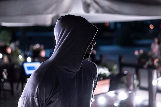 A anonymous person in the night with face under the hood