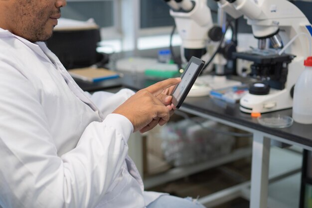 Anonymous researcher using a tablet in a modern laboratory Closeup of his hands typing on the tablet