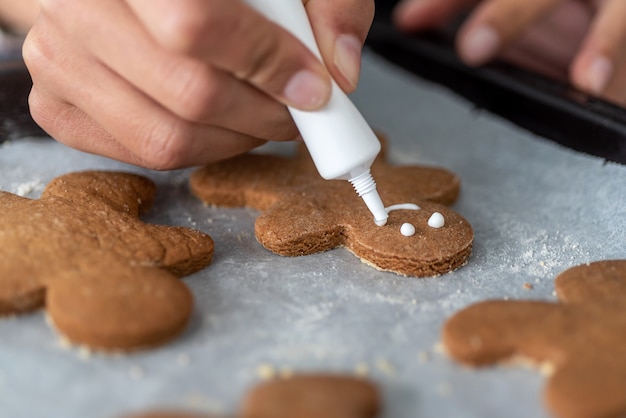 Anonymous woman decorating homemade gingerbread men