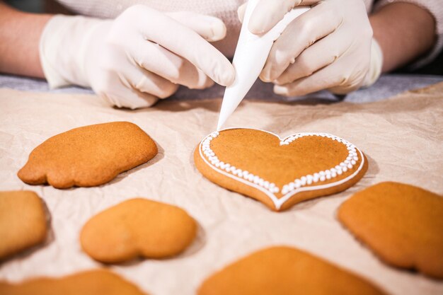 Anonymous woman decorating some homemade gingerbread cookies at kitchen