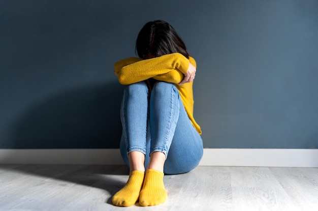 Anonymous woman in depression sitting on floor at home