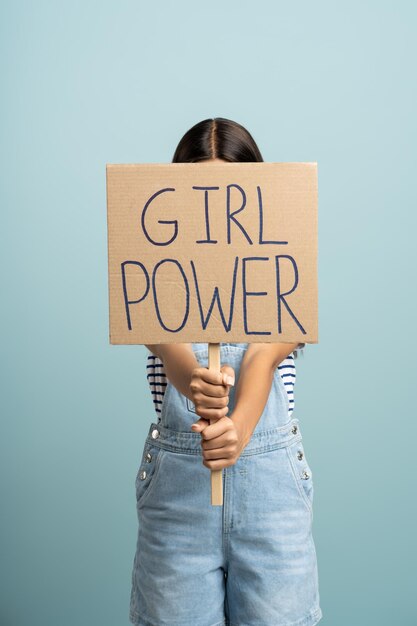 Foto donna anonima con uno striscione lo slogan del potere femminile isolato sullo sfondo blu dello studio i diritti delle donne