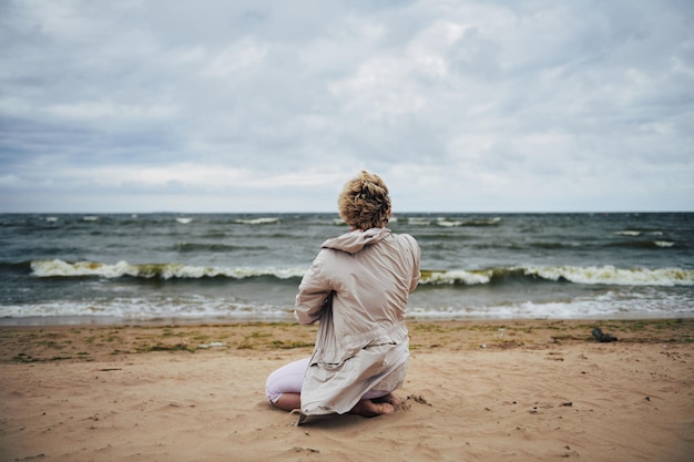 Donna anonima in giacca che guarda il mare