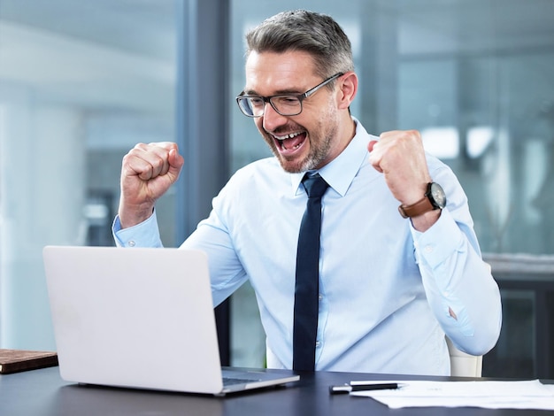 Photo another win for the day shot of a mature businessman cheering while working in an office