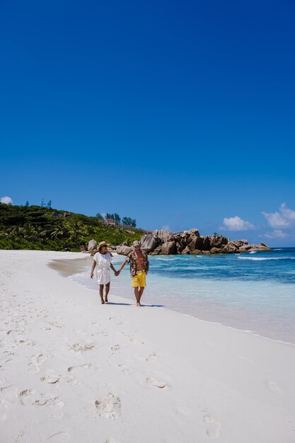 Anse cocos beach la digue island seyshelles drone aerial view of la digue seychelles bird eye viewof tropical island couple men and woman walking at the beach during sunset at a luxury vacation