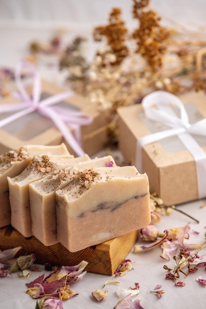 Ansichtkaart met handgemaakte natuurlijke zeep op een houten zeepbakje een geschenkdoos met een lint en droge bloemblaadjes eromheen