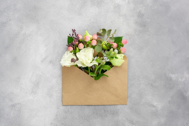 Ansichtkaart met open envelop van kraftpapier gevuld met lentebloemen