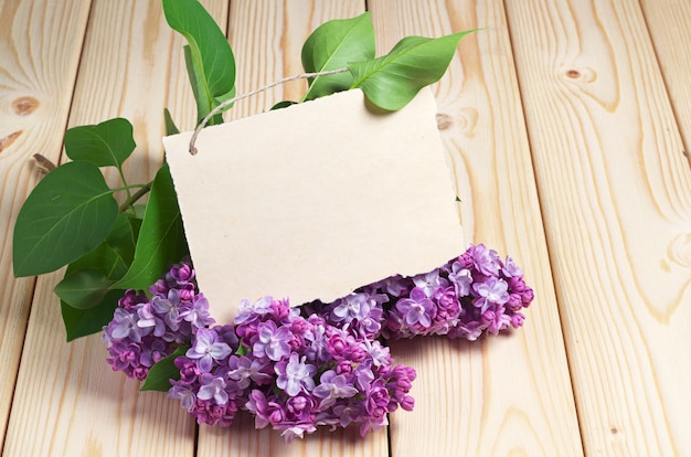 Ansichtkaart met violet lila bloemen op houten tafel