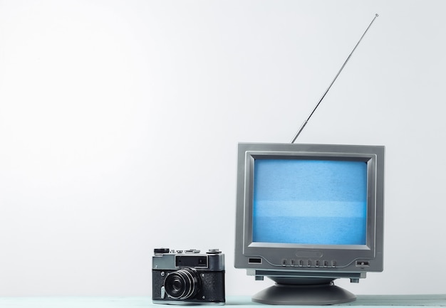 白い壁に昔ながらのレトロなテレビ受信機とフィルム カメラ