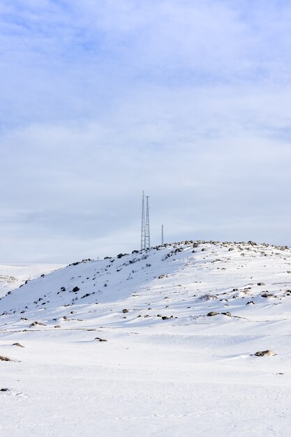 Antenna telecommunications tower covered in white frost in winter mountains.