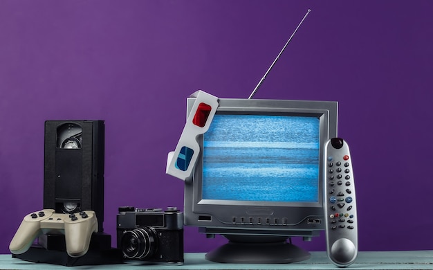 Antenne ouderwetse retro tv-ontvanger, anaglyph stereobril, audio- en videocassette, gamepad, camera, afstandsbediening op paars.