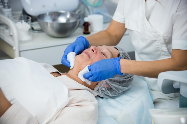 Anti-aging behandelingen cosmetologie kliniek een anti-aging procedure het gezicht afvegen met een wattenschijfje