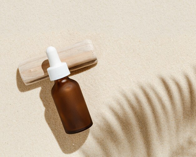 Anti aging serum with collagen and peptides in dark glass bottle with dropper on sandy background