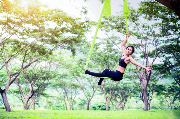 Anti-gravity yoga or aerial yoga at outdoor with public park; Acrobatic fly..