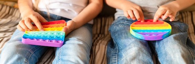 Foto giocattoli pop sensoriali antistress nelle mani di un bambino. un bambino felice gioca con un semplice giocattolo con fossette a casa.