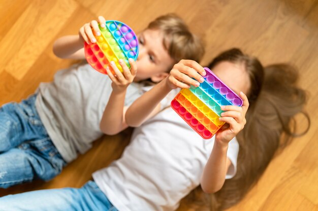 антистресс сенсорные игрушки pop it в детских руках маленькие счастливые дети играют с игрушкой дома