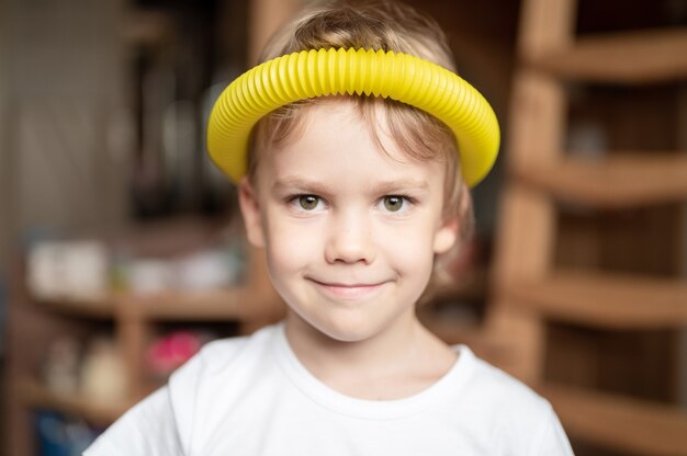 Giocattolo di plastica con tubo pop sensoriale anti stress nelle mani dei bambini. un piccolo bambino felice gioca con un giocattolo di fidget poptube a casa. bambini che tengono e giocano a tubi pop colori multicolori, tendenza 2021 anno