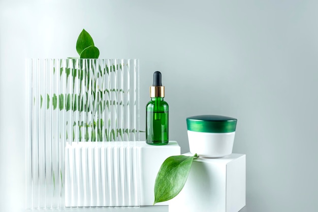 Siero facciale antietà al collagene in bottiglia di vetro verde e crema per il viso su sfondo bianco podio con spazio copia concetto di bellezza cosmetica biologica naturale mockup per il branding