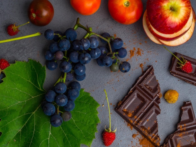 Anticancer food good for cardiovasculas system fresh ripe grape dark chocolate raspberries tomatoes apple on concrete background Food rich in resveratrol antioxidants