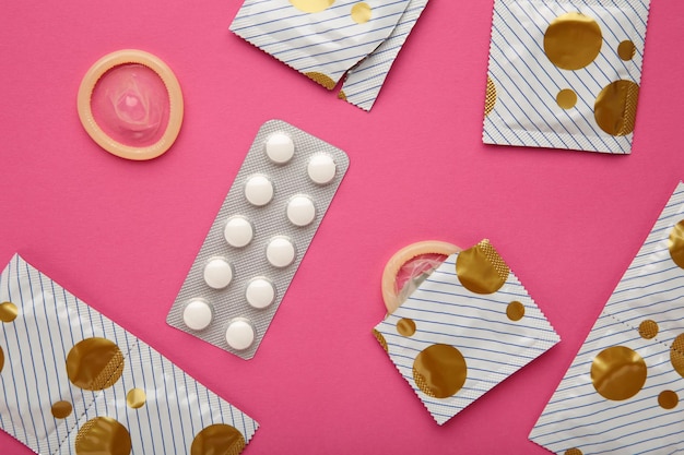 Anticonceptiepillen en condooms op roze achtergrond Concept van anticonceptie