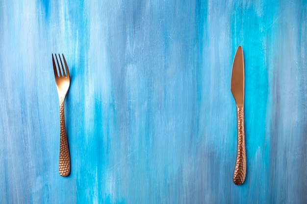 Antiek mes en vork op blauwe achtergrond.