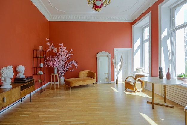 Antiek vintage interieur in 19e-eeuwse stijl woonkamer met felrode muren, houten vloer en direct zonlicht in de kamer.