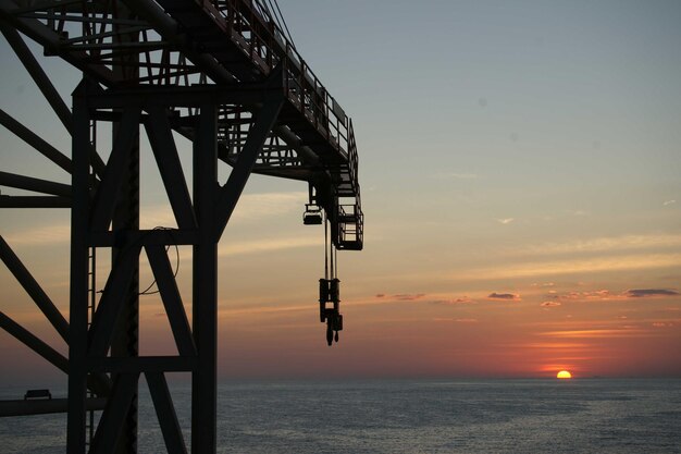 Foto immagine anti-luce della piattaforma petrolifera e del tramonto