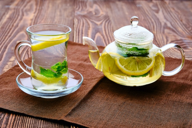 Antioxidant hot drink with lemon and mint in transparent tea pot and glass