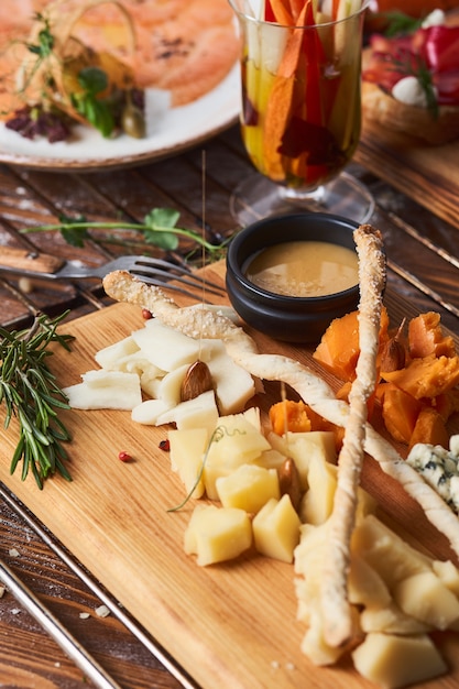 Antipasti, different types of cheese on a wooden board with honey