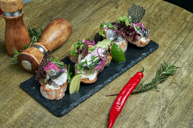 Antipasto - bruschetta met licht gezouten sprot of haring, fetakaas op een Frans stokbrood op een stenen dienblad. Geweldig voorgerecht voor het hoofdgerecht