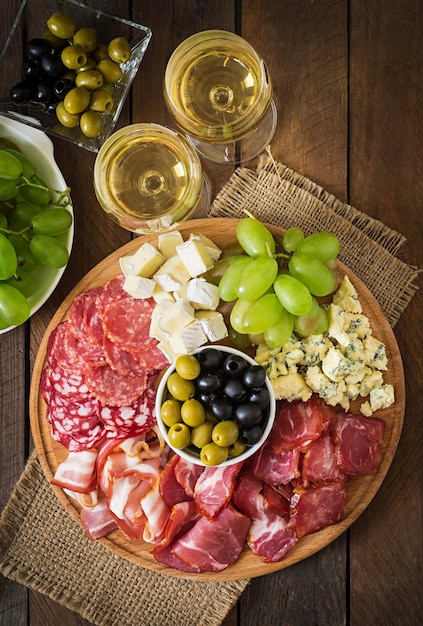 Antipasto catering platter with bacon jerky salami cheese and grapes on a wooden background
