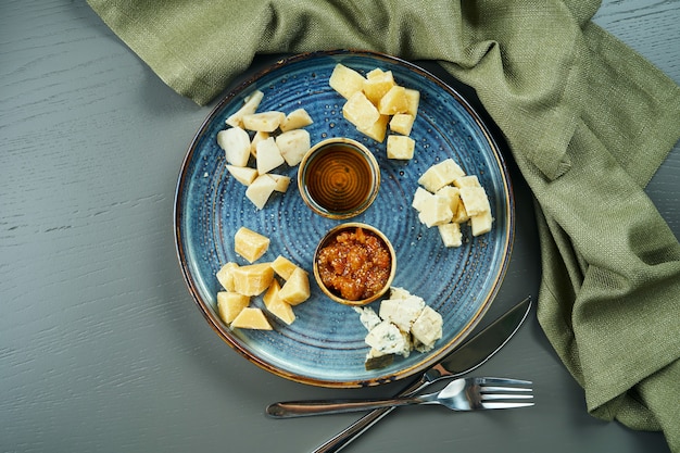 Antipasto - een kaasplateau. verschillende, zelfgemaakte kazen op een keramisch bord - brie, camembert, hollands met honing en noten. wijn voorgerecht. bovenaanzicht, plat lag, kopieer ruimte