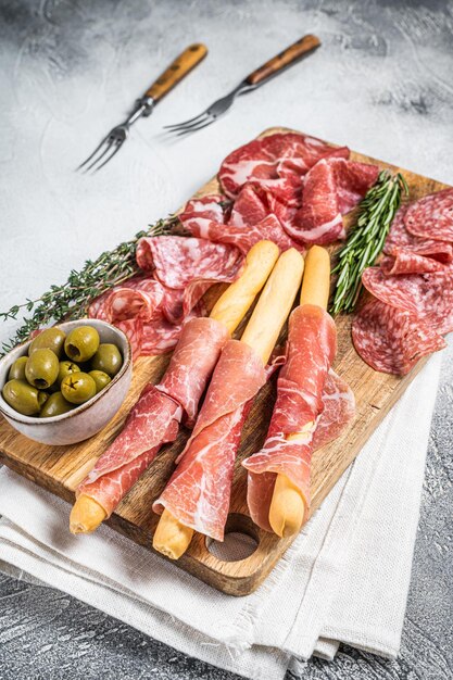 Antipasto platter cold meat plate with grissini bread sticks Prosciutto crudo Salami and Coppa Sausage White background Top view