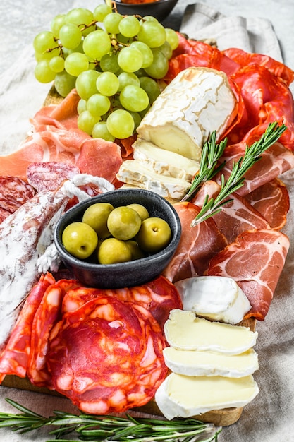 Foto piatto di antipasti di carne fredda con uva, prosciutto, fette di prosciutto, carne secca, salame di chorizo, fuet, camembert e formaggio di capra. vista dall'alto.