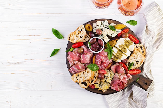 Photo antipasto platter with ham, prosciutto, salami, blue cheese, mozzarella with pesto and olives. top view, overhead