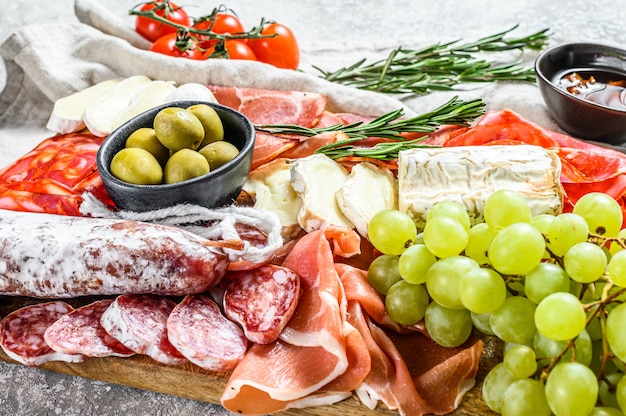 Antipasto set platter. Cold smoked meat plate with sausage, sliced ham, prosciutto, bacon, olives. Appetizer variety.  Gray background. Top view