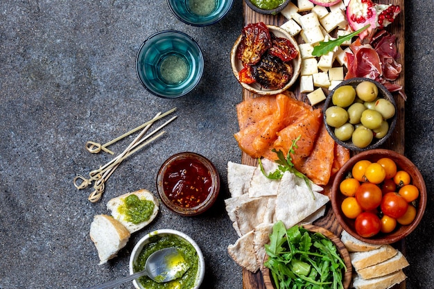 Antipasto Wine set appetizer Ham serrano smoked salmon dried and fresh tomatoes olive cheese wine on board Top view gray cncrete background