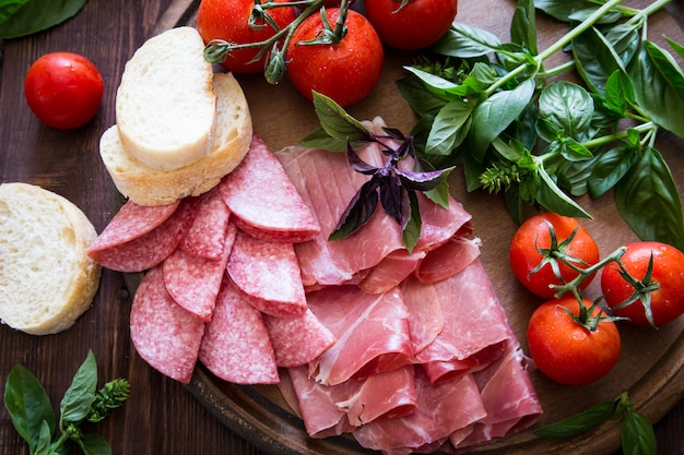 Antipasto with ham, bresaola and salami. bread, tomato and basil.