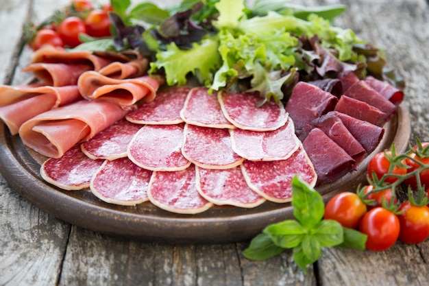 Antipasto with ham, salami and bresaola. tomato and basil. selective focus