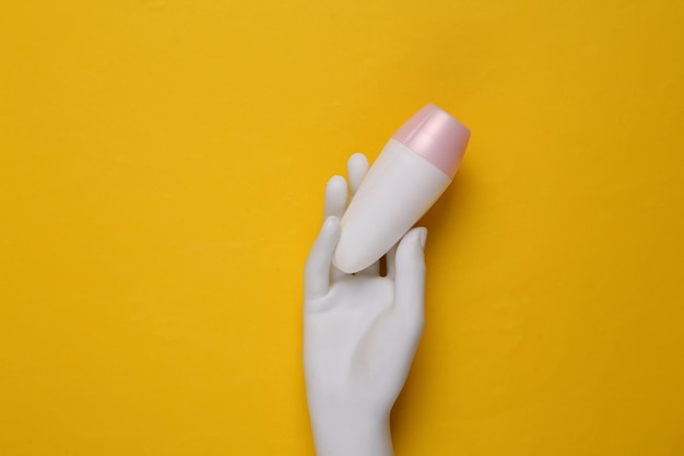 Antiperspirant in mannequin hand on yellow background