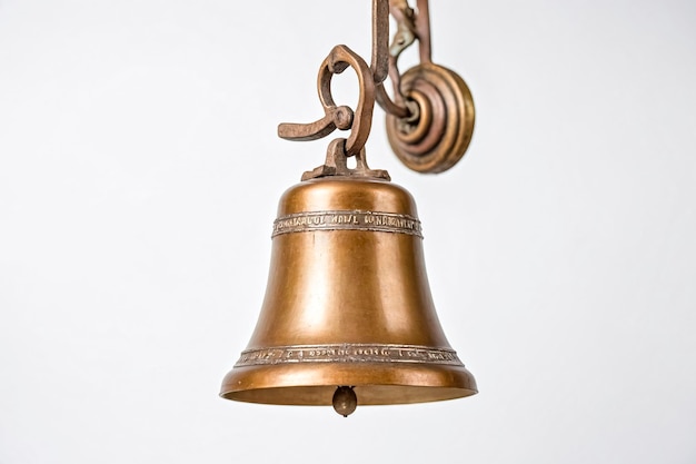 Antique Brass Bell Hanging from an Ornate Wall Mount