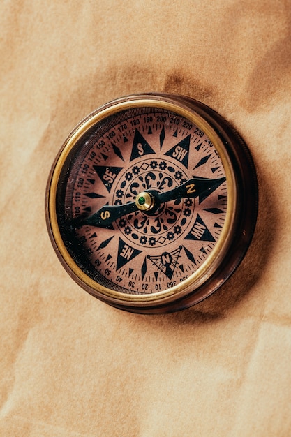 Antique brass compass over old paper