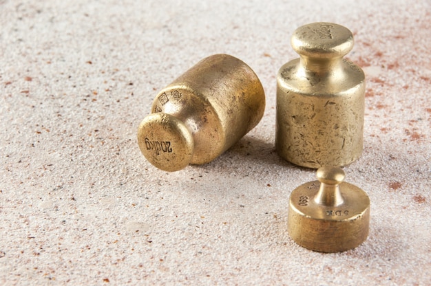 Photo antique bronze weights for scales on concrete background.