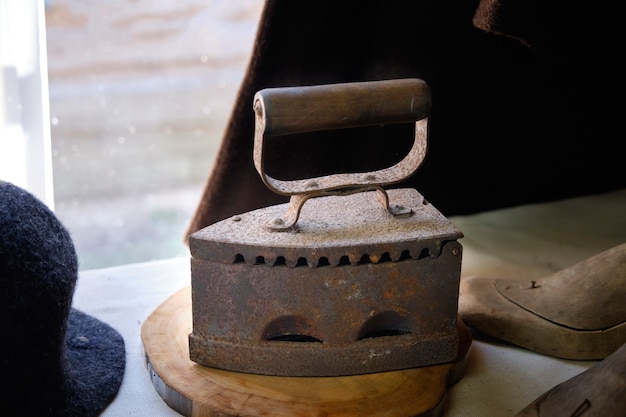 An antique charcoal iron stands on a wooden stand