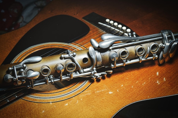 Photo an antique clarinet resting on acoustic guitar