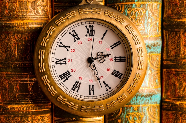 Antique clock on the background of vintage books.