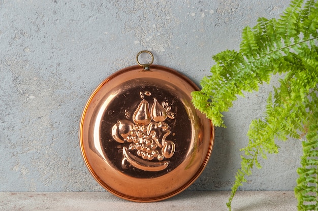 Antique copper cake mold on a concrete table.
