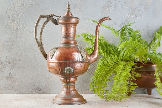 Antique copper jug with lid on concret background.