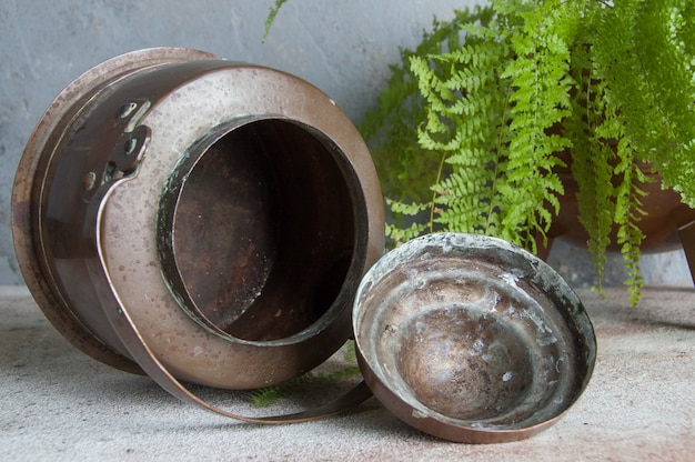 Antique copper kettle on concrete . 