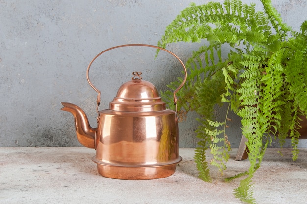 Antique copper kettle on concrete . 